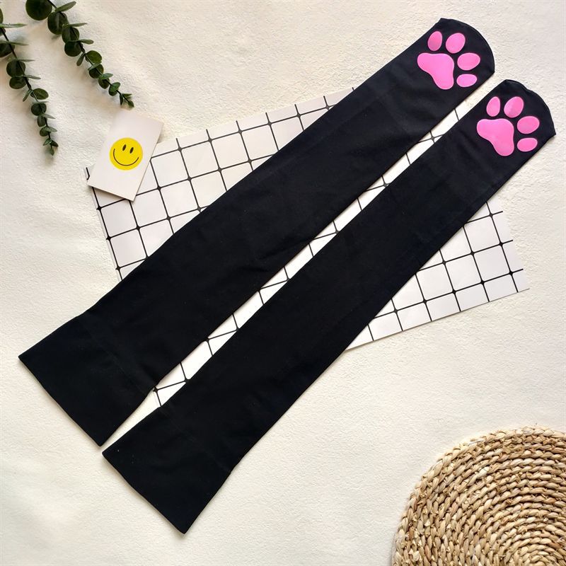 Flatlay view of black cat paw femboy stockings featuring pink paw pad details – playful femboy stockings, cute femboy accessories aesthetic