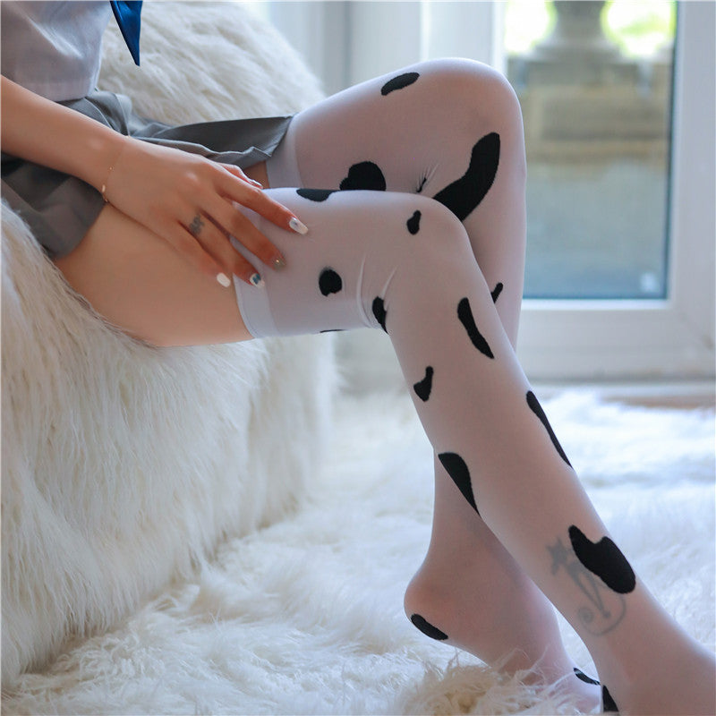 Close-up of cow print thigh high stockings pattern detail, black and white femboy hosiery