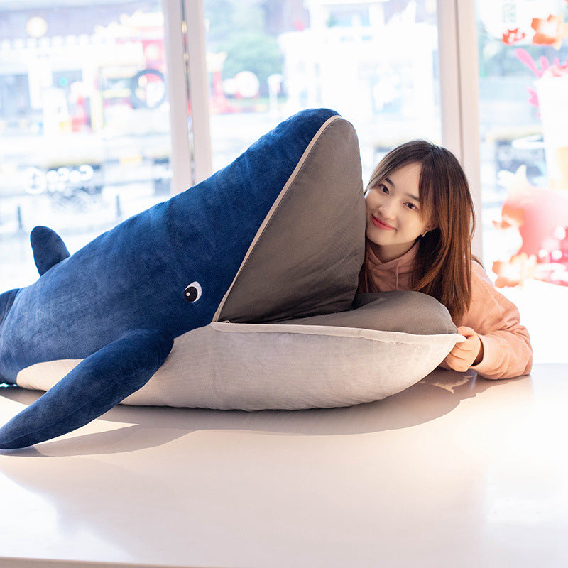 Close-up lifestyle shot of a model hugging the Femboy BLÅVINGAD whale plush on a tabletop, taken from a low front-facing angle with soft daylight tones and a blue-grey palette, focusing on comfort and texture, a cozy add-on for casual femboy outfit ideas.