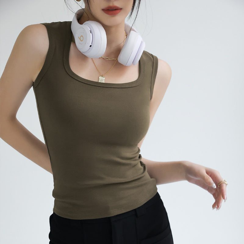 Fitted olive green femboy cotton tank top worn by an androgynous model, sleeveless design with a soft ribbed texture, styled casually with black pants and headphones, minimalist studio background.