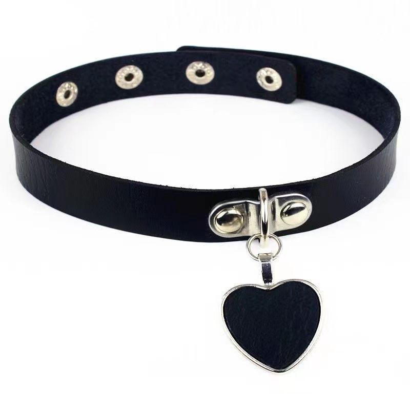 Black femboy gothic choker featuring a silver heart charm, slim faux leather band, adjustable snap buttons, and soft punk aesthetic, photographed on a white background for femboy clothing looks.