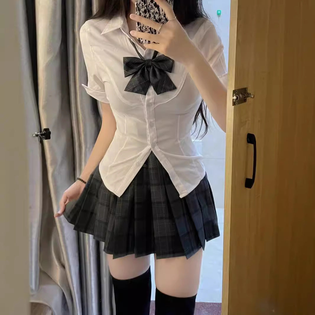 Full look of the Femboy Schoolgirl Kit featuring a white short sleeve shirt with a plaid bow and pleated skirt, perfect for a stylish and edgy femboy outfit.