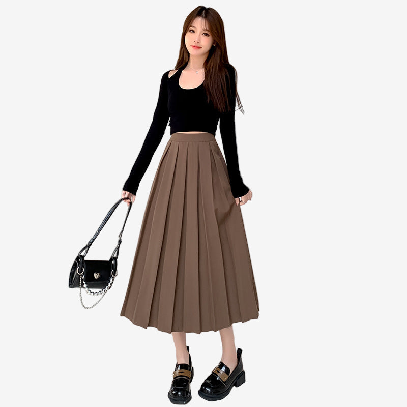 Full-body shot of model in a brown high-waisted pleated skirt with a black crop top and chunky loafers, taken in a stylish, industrial-themed setting. An ideal femboy style look for a chic and bold aesthetic.