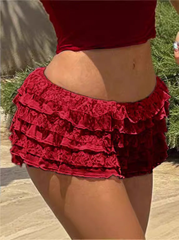 Front view of red tiered lace skirt-pants on a model, showcasing a delicate white lace base with subtle red accents. Captured at eye level in natural light on a neutral backdrop for femboy clothing.
