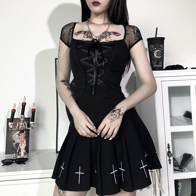 eye-level full-body shot of a model standing against a minimalist white interior wearing a slim-fit lace-up crop top and coordinating skirt, illustrating femboy apparel.