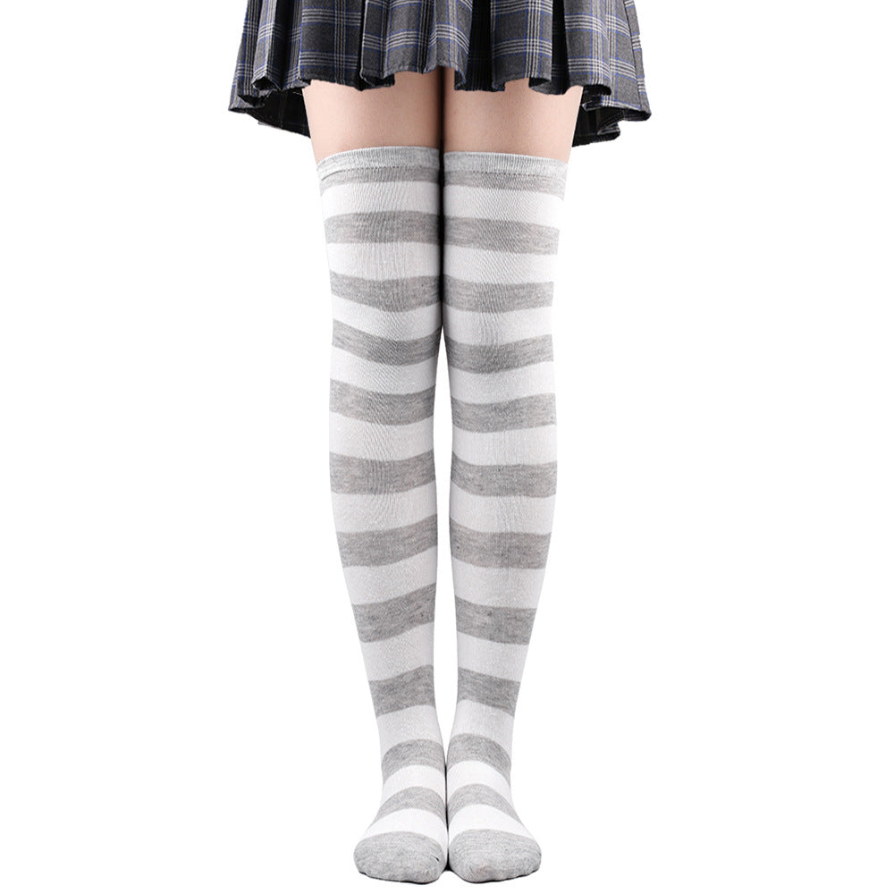 Grey and white striped femboy thigh high socks worn on legs, neutral toned front-facing shot with white background, minimal femboy fashion style.