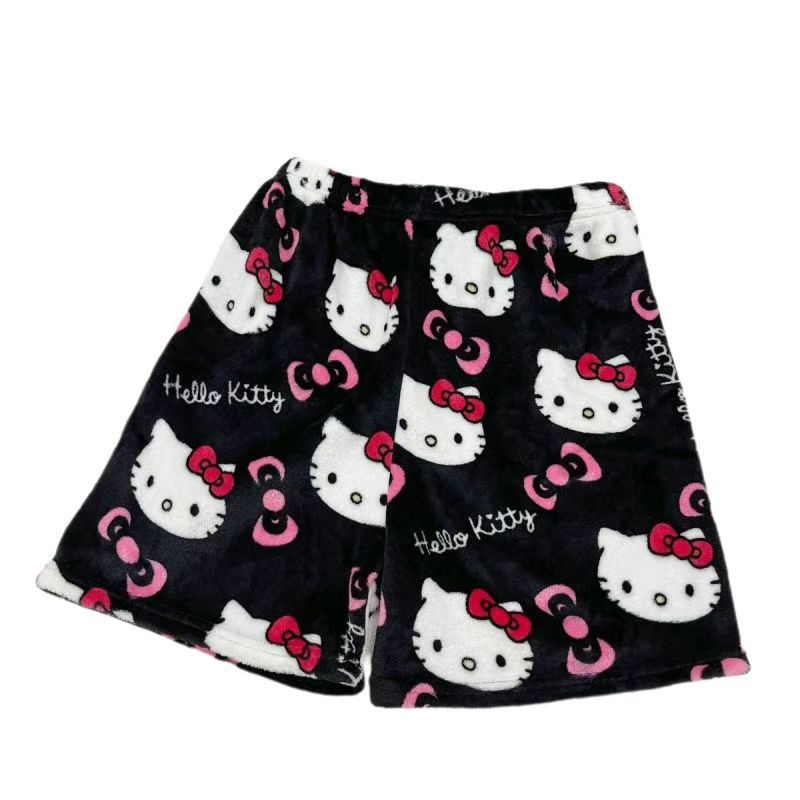 Flat lay front view of black plush Hello Kitty print shorts with large Hello Kitty faces, pink bow icons, and “Hello Kitty” text; elastic waistband; clean white background image for cute femboy clothes.