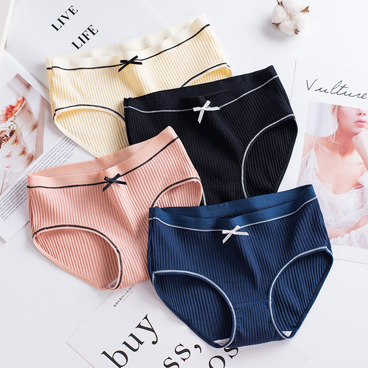 overhead shot of five ribbed briefs in cream, black, peach, navy, and yellow fanned out on a white background, illustrating versatile color options in femboy underwear.