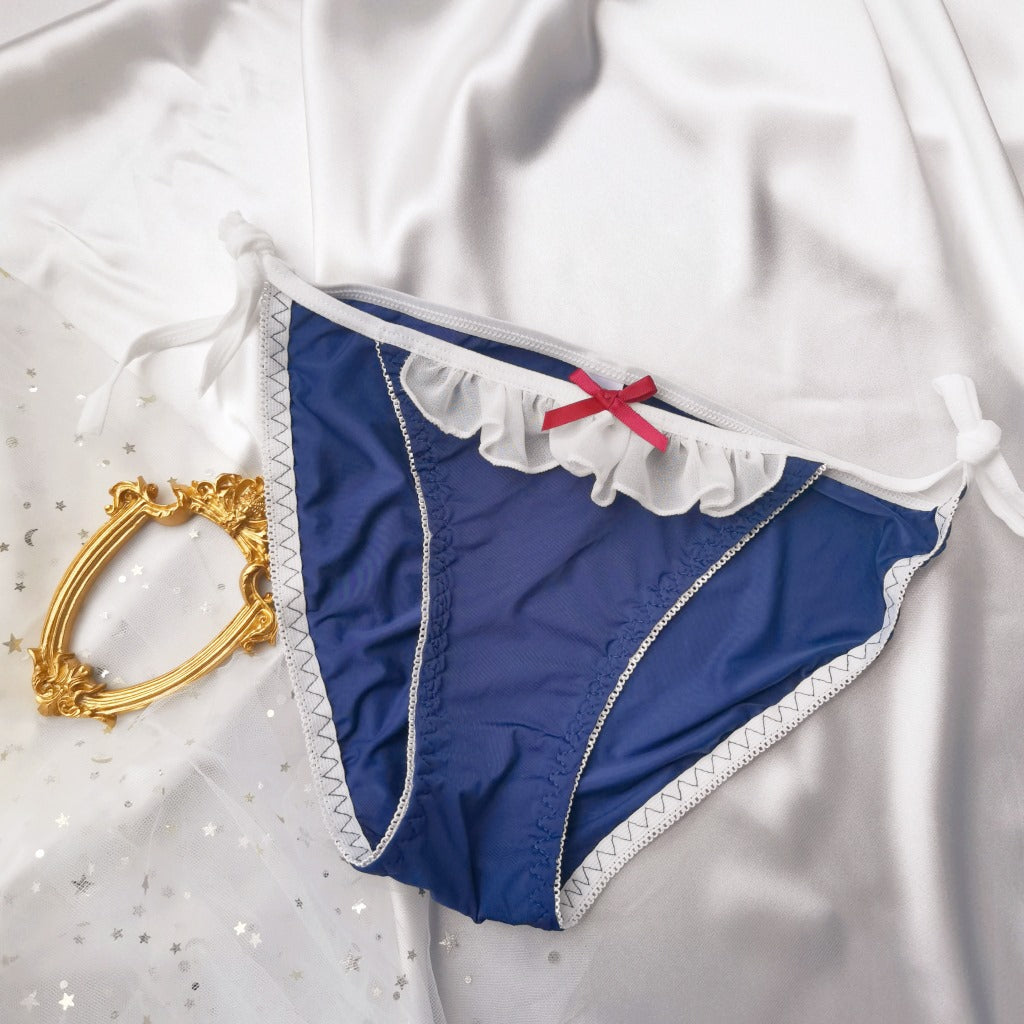 Flat lay of navy blue Lolita maid lace-up panties with frilled white trim and red bow, styled on satin background – cute femboy panties, femboy underwear aesthetic