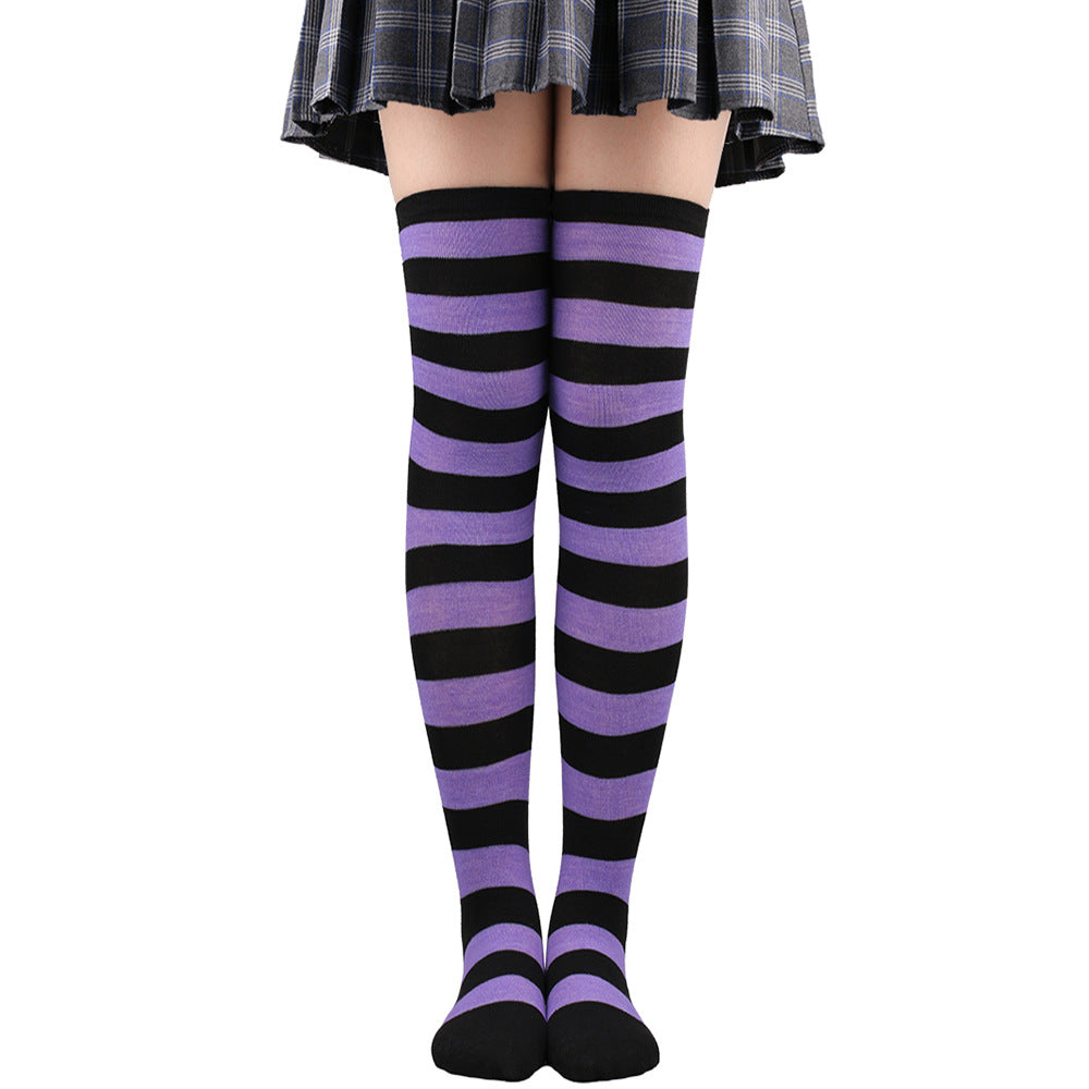 Purple and black striped femboy thigh high socks worn above the knee, centered front view with high-contrast gothic-inspired femboy fashion look.