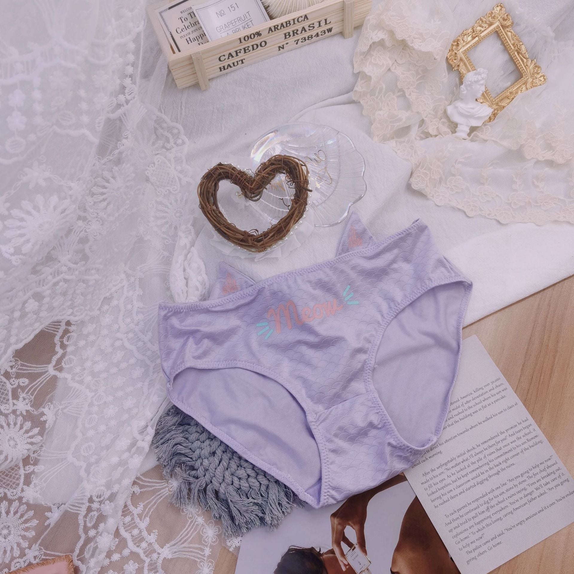 Purple cat pouch femboy panties with meow graphic and textured fabric, aesthetic flat lay product display with lace background