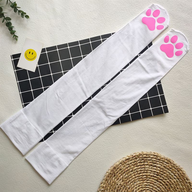 Flatlay shot of white cat paw femboy stockings with pink paw pads on toes, displayed on grid board background – cute femboy hosiery aesthetic, kawaii legwear