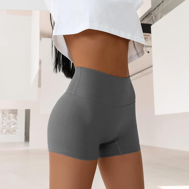 Side view of light gray yoga shorts on a model, highlighting the curve-hugging fit and minimalistic design. The photograph is taken from a low angle focusing on the waist to mid-thigh