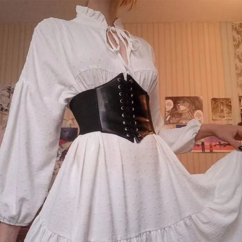 Medium shot of a black corset-style waist belt with lace-up detail worn over a white dress, creating a stylish silhouette. Perfect for femboy outfits, adding elegance to femboy clothes.