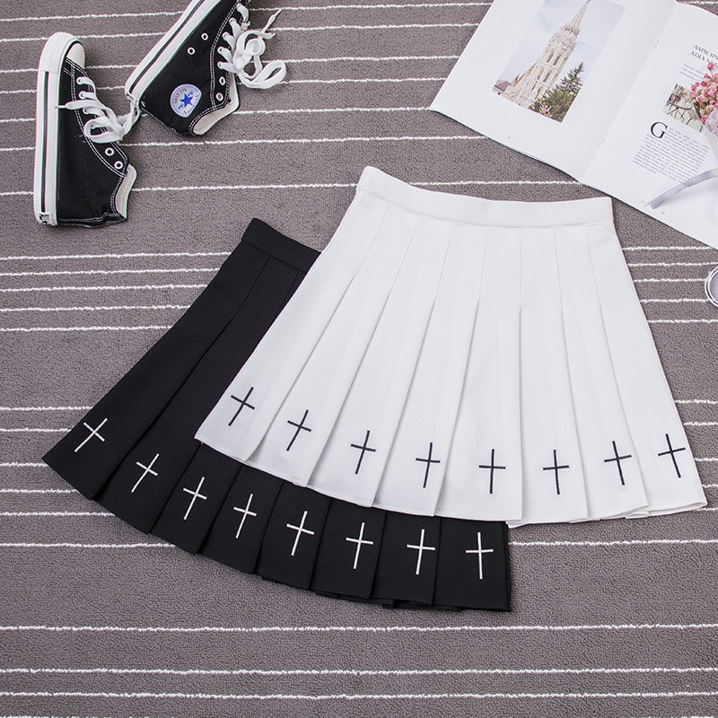 Black Gothic Cross Pleated Skirt on carpet with white crosses at the hem, paired with black Converse shoes.