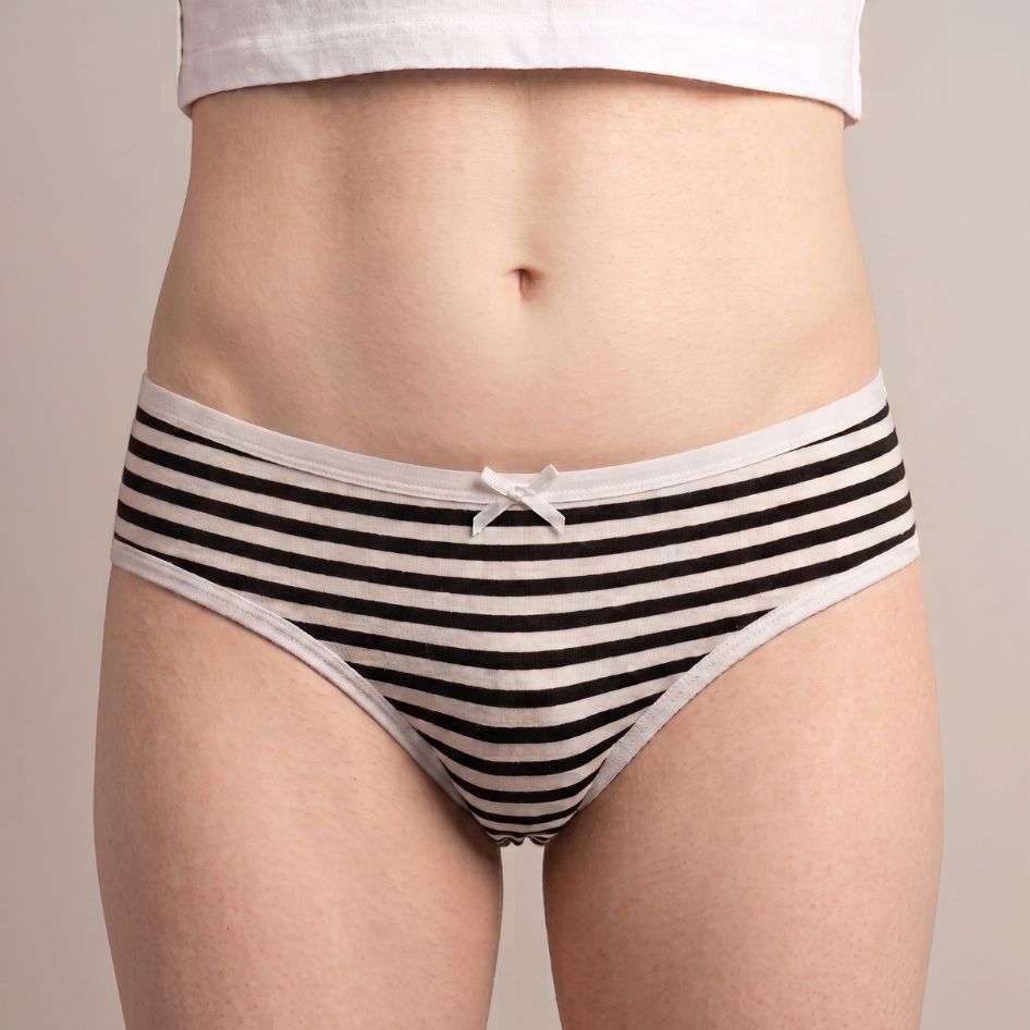 Black and white striped femboy panties with white bow and trim, bikini-cut brief on model, front view | FemboyBox