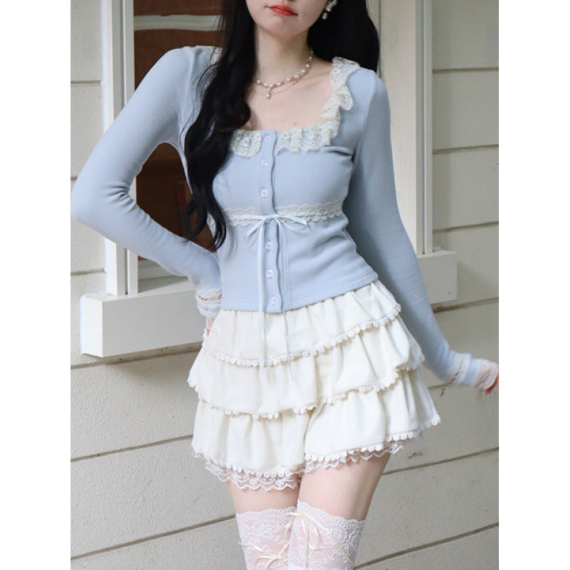 Medium shot of a blue Lace Cardigan Top featuring lace detailing and a flattering fit, styled with a cream layered skirt. Taken outdoors in natural lighting, emphasising femboy fashion and elegant styling.