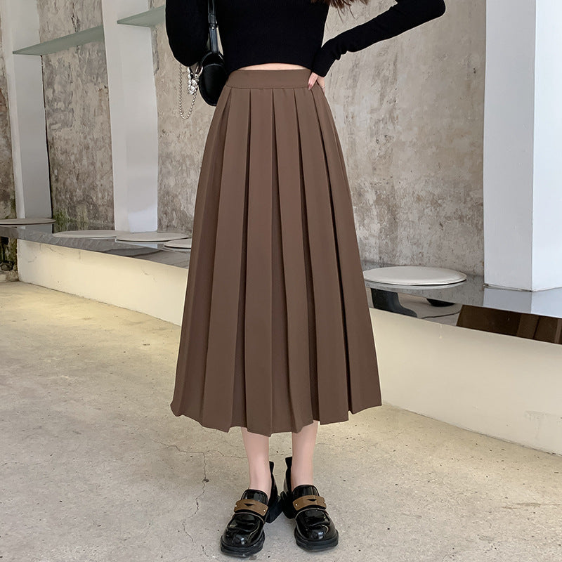 Medium shot of a brown high-waisted pleated skirt styled with a black top and loafers, highlighting elegant femboy style, femboy outfits