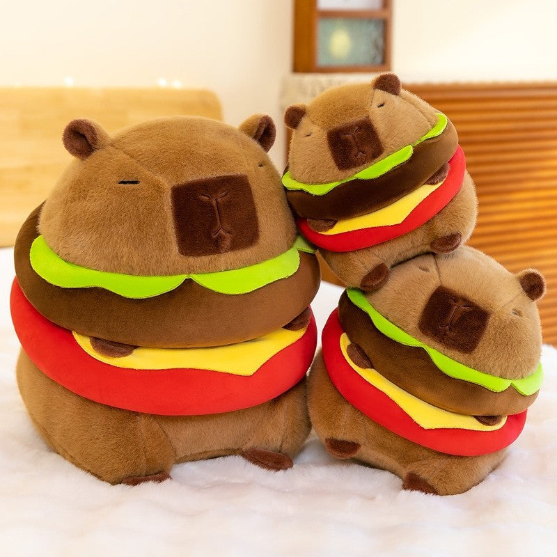 Group display of multiple Capybara Burger Plush toys stacked together, featuring a soft brown capybara plush wrapped in a burger design with bright lettuce, cheese, and tomato layers.