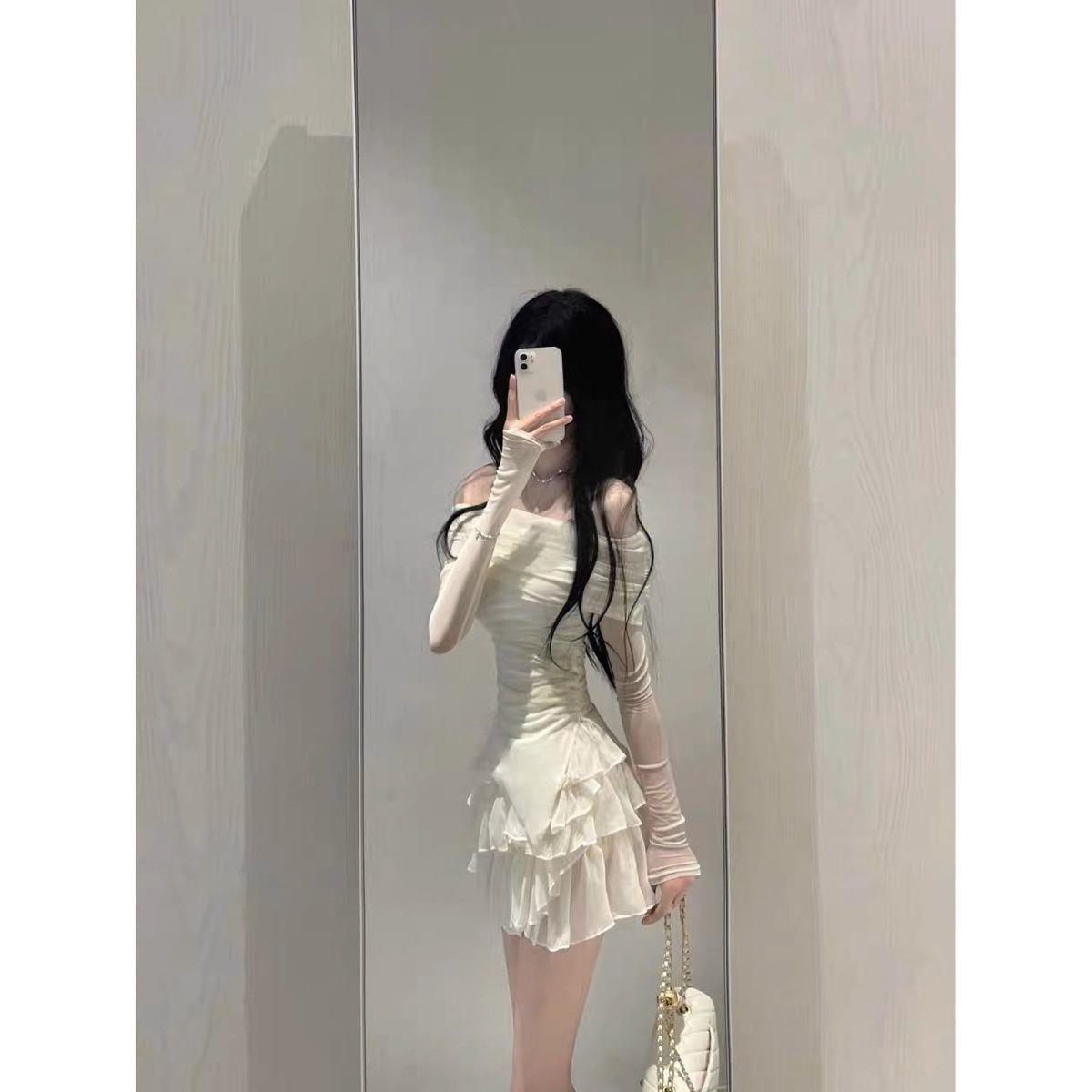 Full-body mirror shot of the Chic Femboy Kit featuring a ruched white off-shoulder top paired with a layered ruffled skirt. Captured indoors with a minimalist background, showcasing modern femboy clothing and fashion aesthetics.