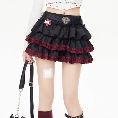 Model wearing a dark punk tiered femboy skirt with black and red ruffled layers, styled with platform boots and accessories, showcasing edgy gothic femboy outfit aesthetics.