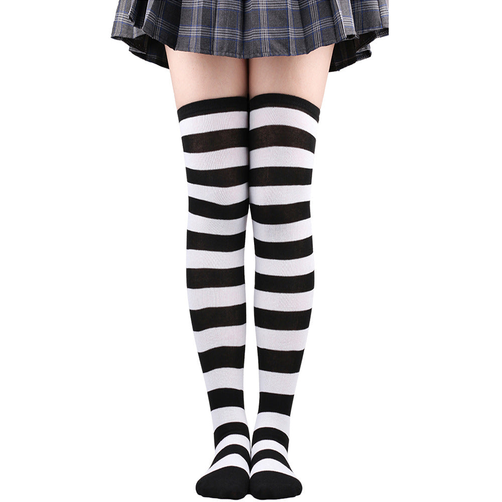 Black and white wide-striped femboy thigh high socks worn on legs, front-facing full-length shot emphasizing high-contrast stripes and stretchy fabric, white background, femboy clothes and femboy fashion.
