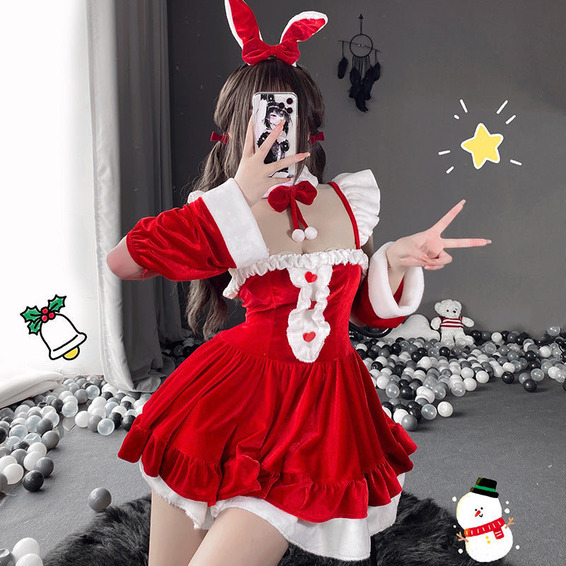 Medium shot of the Christmas Femboy Kit, featuring a layered red velvet dress with fur trim and holiday accessories, creating a playful, festive atmosphere for femboy fashion. Background shows Christmas decor, enhancing the holiday vibe.