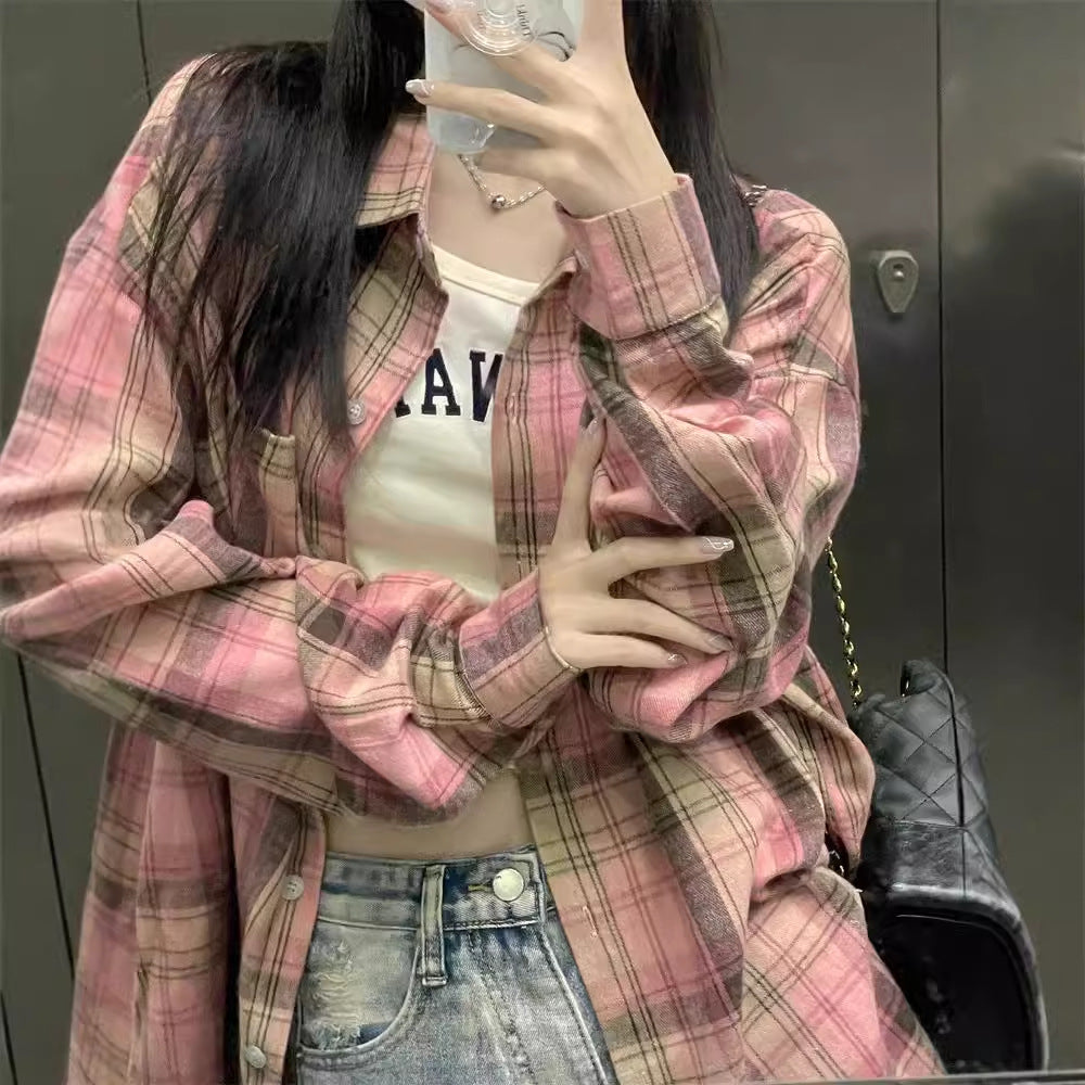 Mirror selfie of a person wearing a pink plaid button-up shirt with a cropped white tank top and high-waisted denim shorts, accessorized with a black purse. This close-up shot emphasizes the stylish elements of femboy clothes.
