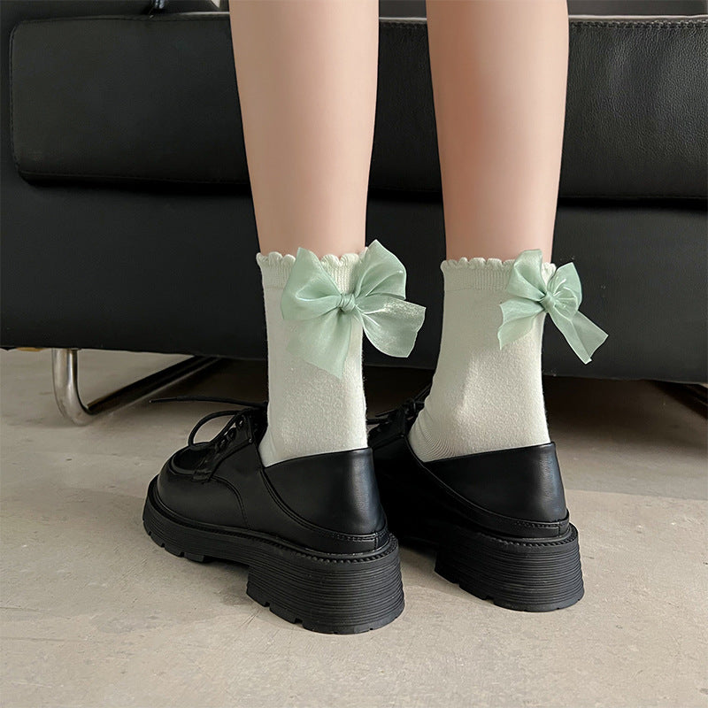 Back view of green bow socks paired with black shoes, showcasing femboy clothing style.