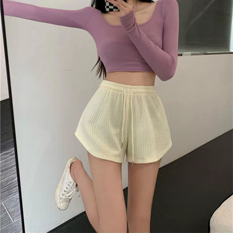 A front view of relaxed femboy athletic shorts in yellow, featuring a high-waist design and loose A-line fit, styled with a purple crop top for a sporty look.