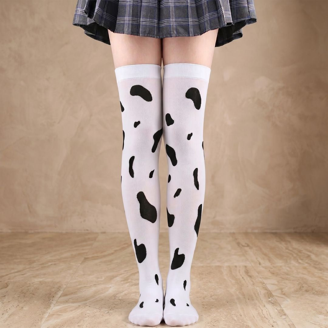 Black and white cow print thigh high stockings worn under plaid skirt, cute femboy hosiery from FemboyBox