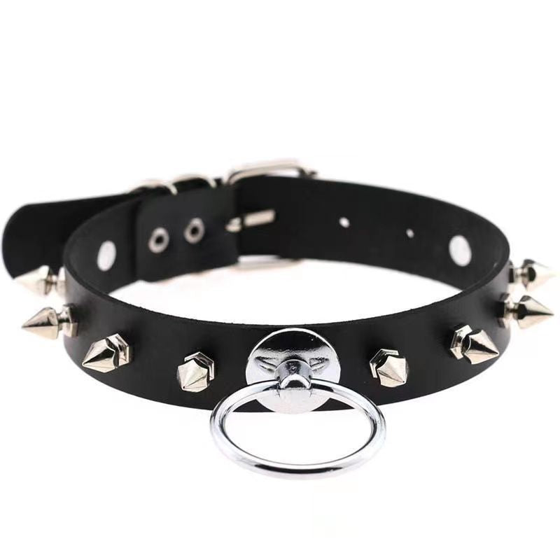 Gothic femboy choker made from black leather with silver studs and front O-ring detail, minimalist white background product image highlighting femboy fashion aesthetics.
