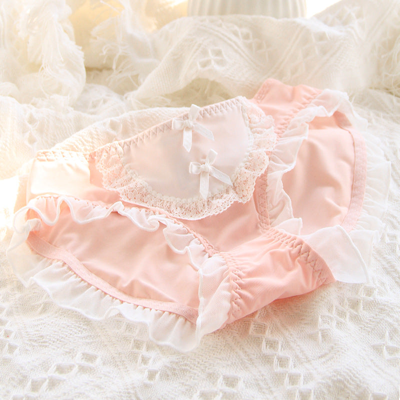 Pale pink Lolita maid panties with delicate lace trimming and subtle bow decorations on a fluffy white background. The soft pastel color and dainty lace work align with femboy fashion's gentle and graceful style.