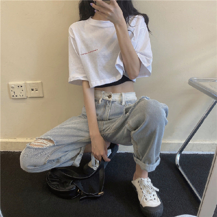 Casual femboy outfit featuring a loose white crop top paired with distressed jeans, highlighting a relaxed streetwear aesthetic.