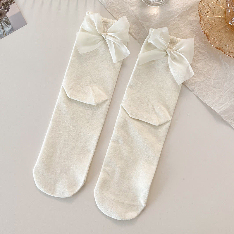 Top view of two Lolita Princess Socks in creamy white with lace trim and a back bow, arranged neatly on a light background.