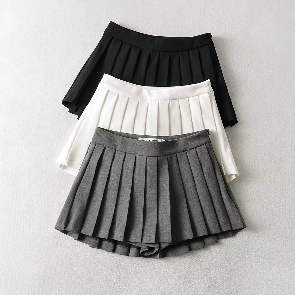 A collection shot of Femboy Tennis Skirts in grey, white, and black, neatly laid out on a flat surface with contrasting labels for each. This composition emphasizes the variety and tailored fit of the skirts.