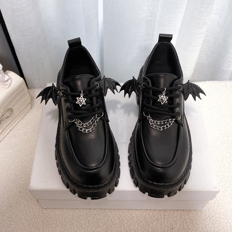 Front view of Gothic Lolita School Pumps featuring a glossy black finish with winged accents and decorative chains, showcasing a unique star pendant on the laces. Ideal for femboy fashion with a dark, elegant twist.