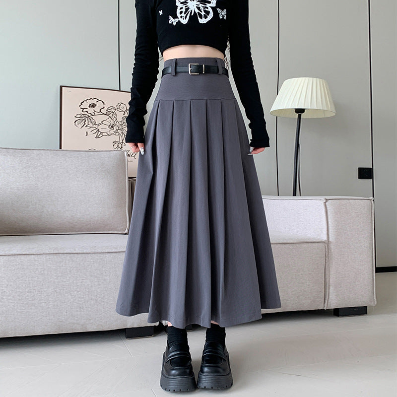 Medium shot of a model in a gray midi pleated skirt with a belt, high-waisted, styled as femboy clothing, set against a contemporary room background with soft lighting.