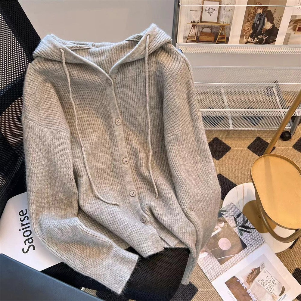 Elegant grey knit femboy hoodie with button details, draped on a chair, showcasing a relaxed fit for chic femboy clothing and everyday femboy outfits.