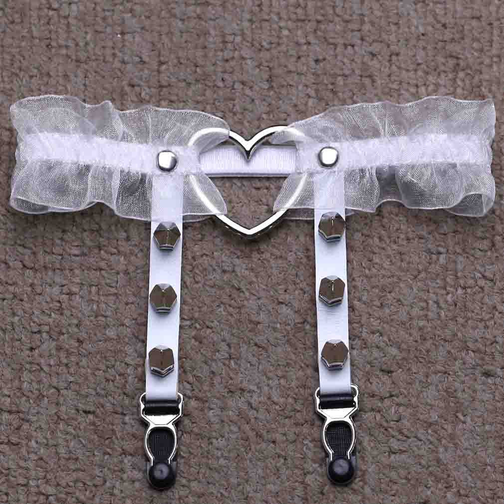 Overhead studio flat lay of the white Heart Lace Femboy Garter photographed on a textured neutral surface, showcasing translucent white lace, silver heart centerpiece, and adjustable strap clips, a delicate femboy garter accessory for clean and aesthetic femboy outfits.