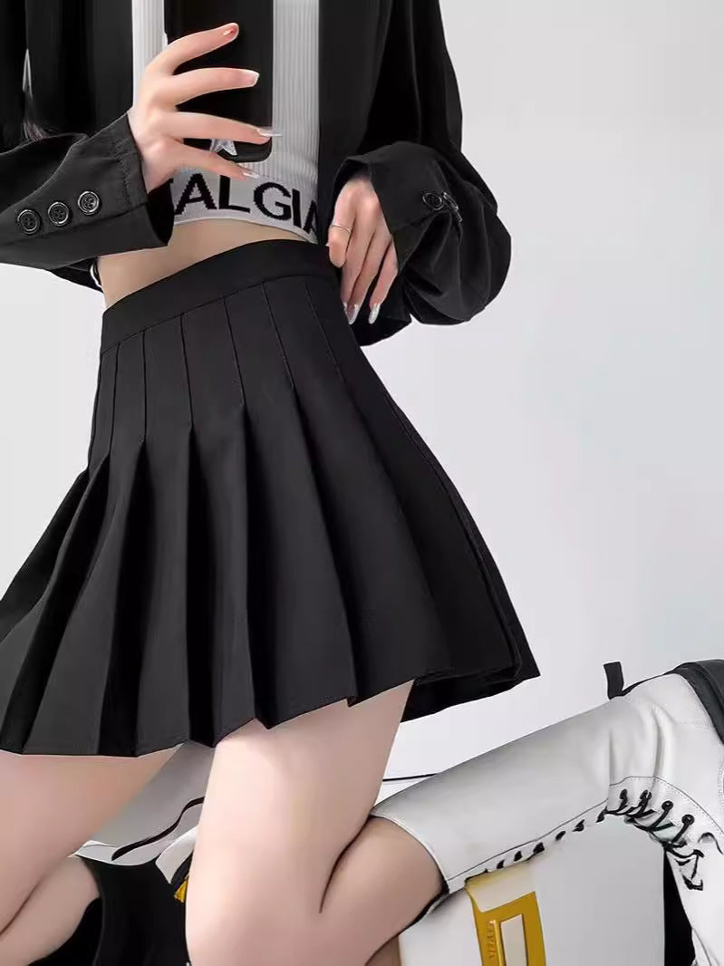 A chic black pleated skirt worn by a model paired with a black oversized jacket, photographed in an indoor studio setting. This versatile black skirt is a stylish addition to any femboy clothing collection, ideal for creating modern and sleek femboy outfits.