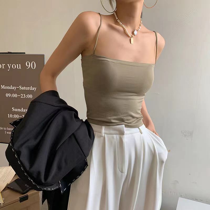 A model showcasing a khaki green padded long camisole, paired with white trousers, styled for a chic and casual femboy fashion look, blending comfort and elegance in femboy clothing.