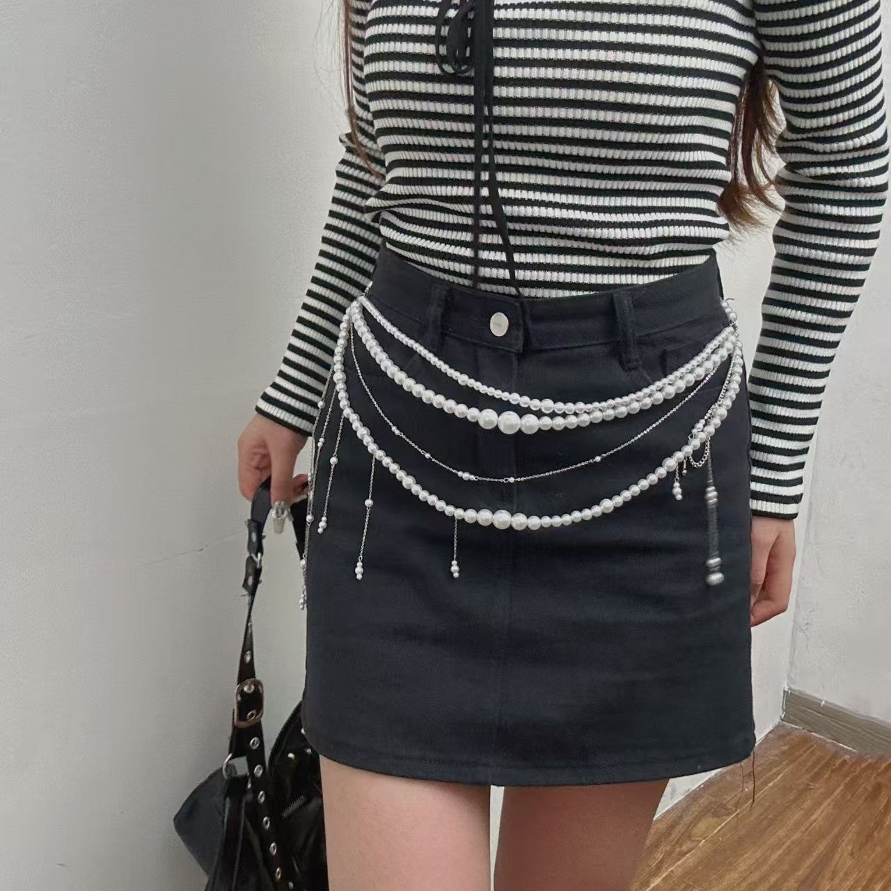 Pearl drape waist body chain worn over black skirt, femboy outfit accessory lifestyle shot