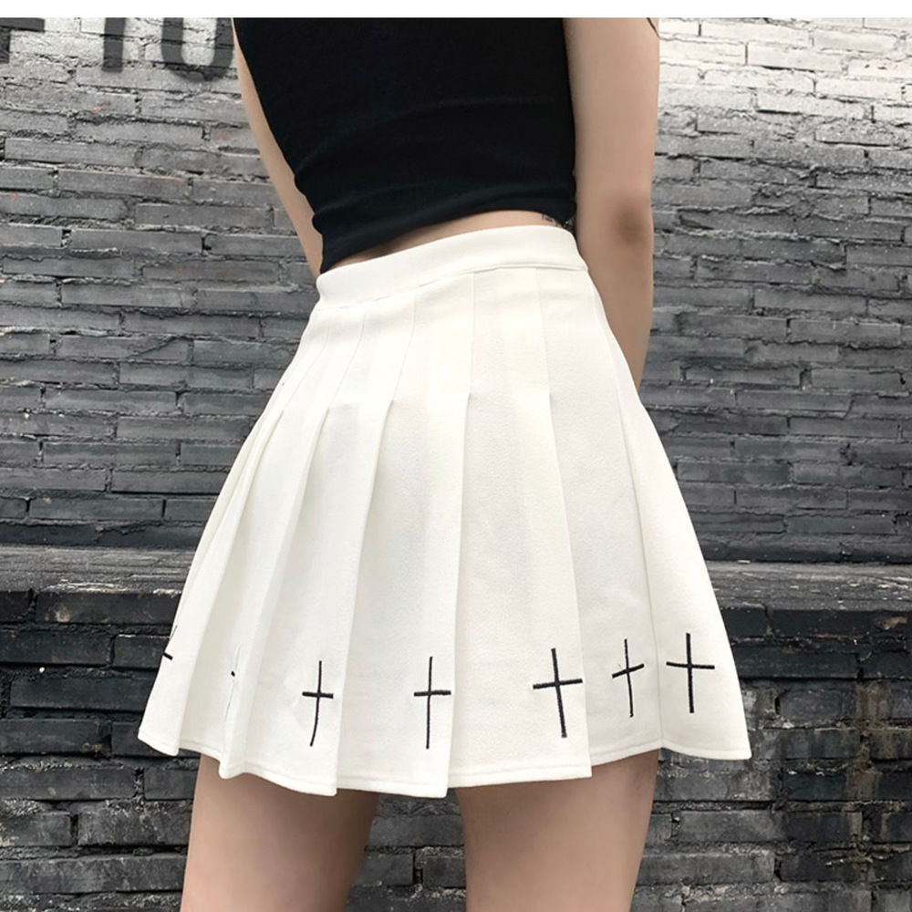 White gothic cross pleated skirt styled in edgy femboy fashion outfit, high waist design with clean structured pleats against urban brick background