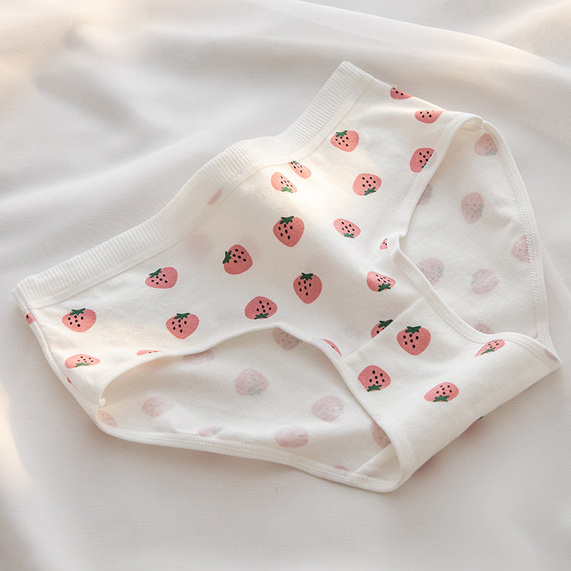 A white pair of strawberry print panties with small, cute strawberries scattered across the fabric. The close-up shot highlights the playful design, ideal for femboy fashion and breathable femboy outfits. The background is softly lit with natural sunlight.